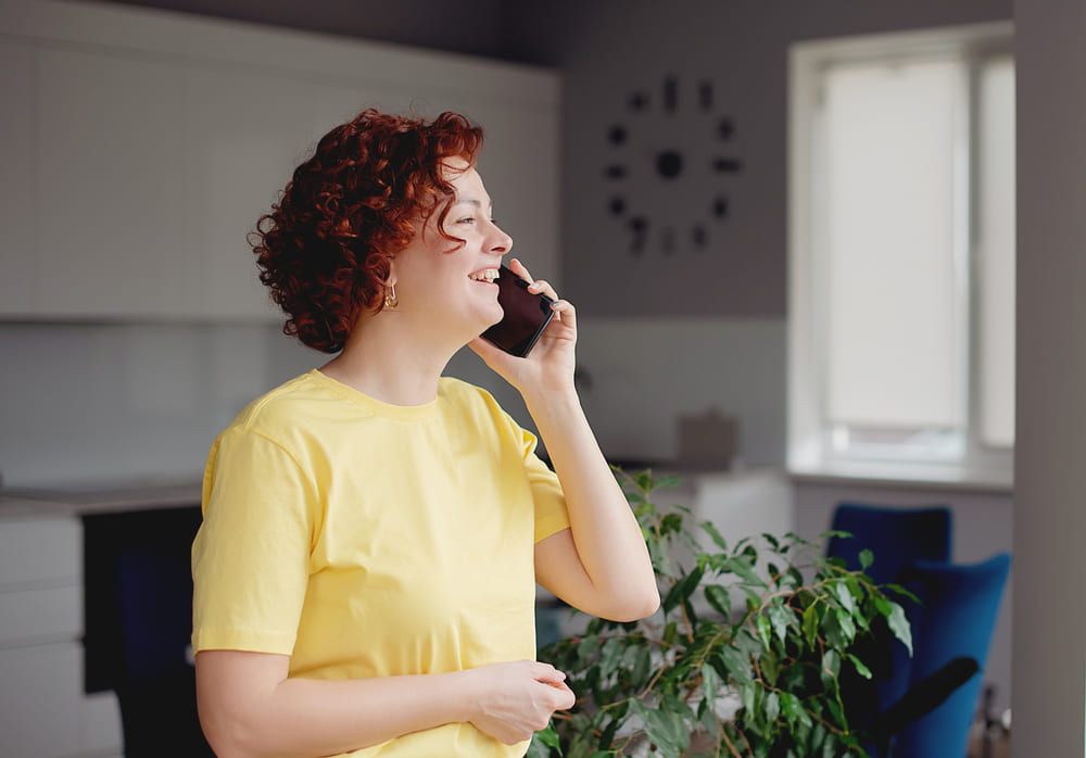 Kobieta rozmawia przez telefon: pyta się o właściwości cateringów i o to, czy można je łączyć z kawą bezkofeinową. 